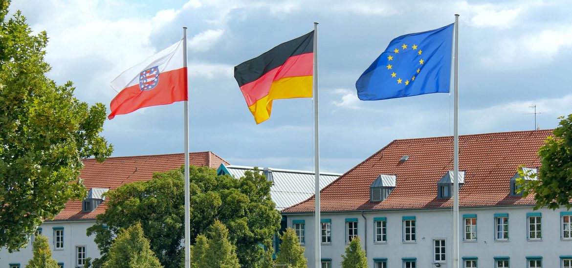 Außenansicht Thüringer Finanzministerium in Erfurt mit den wehenden Flaggen von Thüringen, der BRD und der EU im Vordergrund