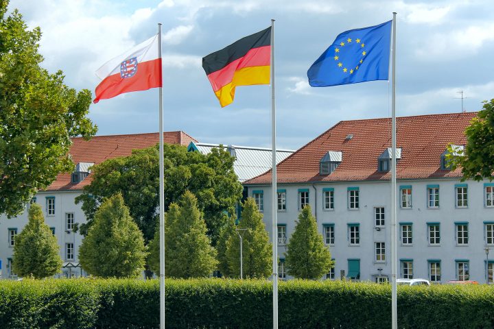 Außenansicht Thüringer Finanzministerium in Erfurt mit den wehenden Flaggen von Thüringen, der BRD und der EU im Vordergrund