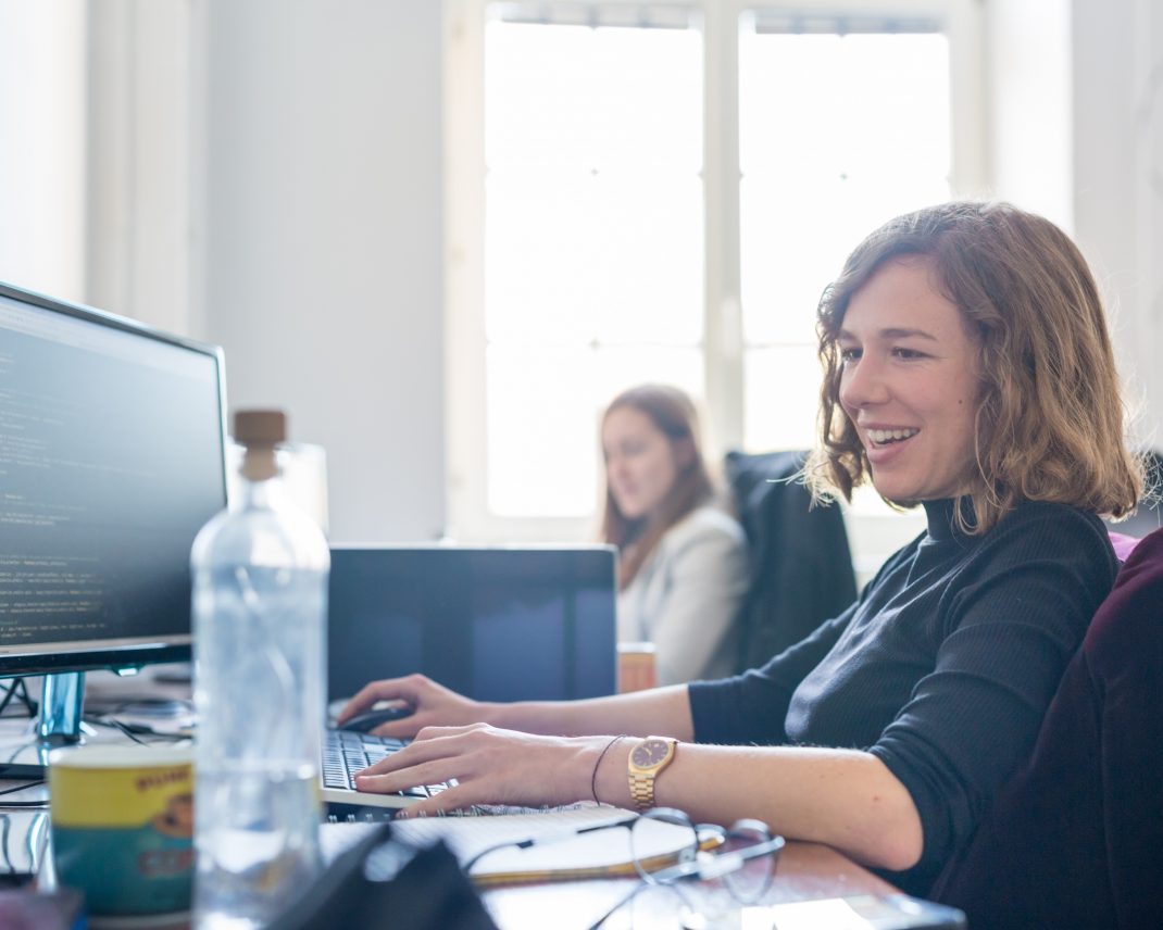 2 junge Frauen im Büro betrachten Ihre Computer Bildschirme und lächeln dabei Copyright: ©Adobe Stock 183347798